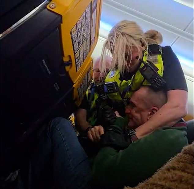 An intoxicated British Ryanair passenger had to be wrestled by police after refusing to sit down for landing - forcing the pilot to circle the airport