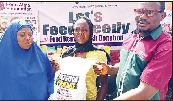 Durosomo (right) assisted by his wife, Hajia Ganiyyah Yusuf to present the food items to a beneficiary.