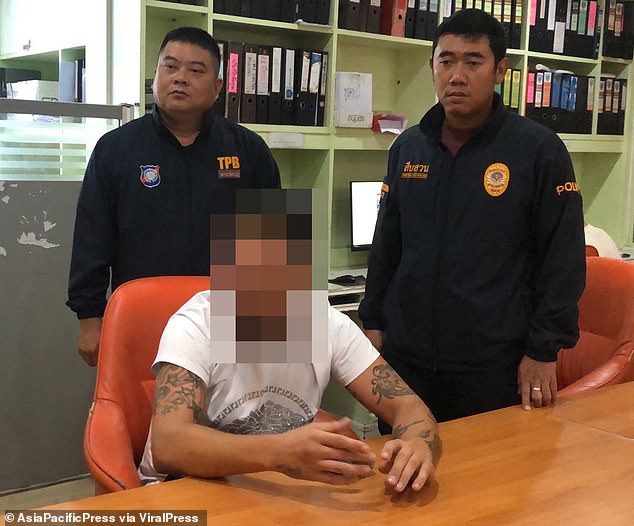 The Welshman is pictured in custody with Thai police after allegedly striking the Russian