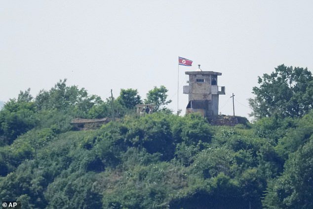 North Korean soldiers stand near their military guard post as a North Korean flag flutters in the wind, seen from Paju, South Korea, Sunday, June 9, 2024
