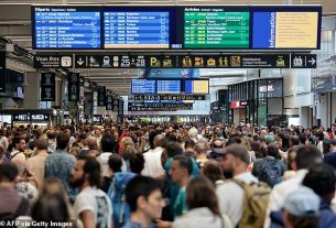 Passengers gather around the departure boards at the Gare Montparnasse train station in Paris on July 26, 2024 as France's high-speed rail network was hit by malicious acts disrupting the transport system hours before the opening ceremony of the Paris 2024 Olympic Games