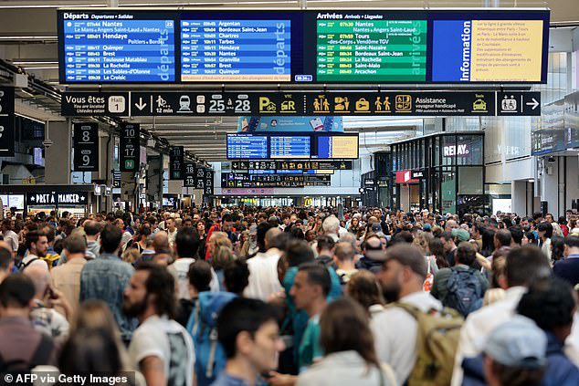 Passengers gather around the departure boards at the Gare Montparnasse train station in Paris on July 26, 2024 as France's high-speed rail network was hit by malicious acts disrupting the transport system hours before the opening ceremony of the Paris 2024 Olympic Games